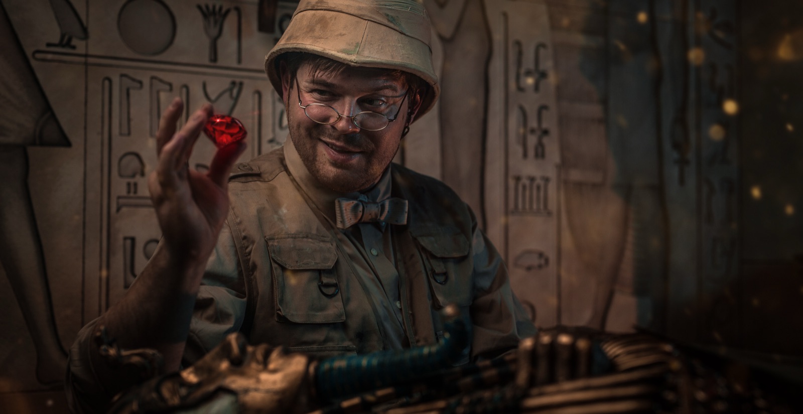 An explorer in a pith helmet holds up a red ruby among the hieroglyphs inside Quest Room’s Red Giant escape room.
