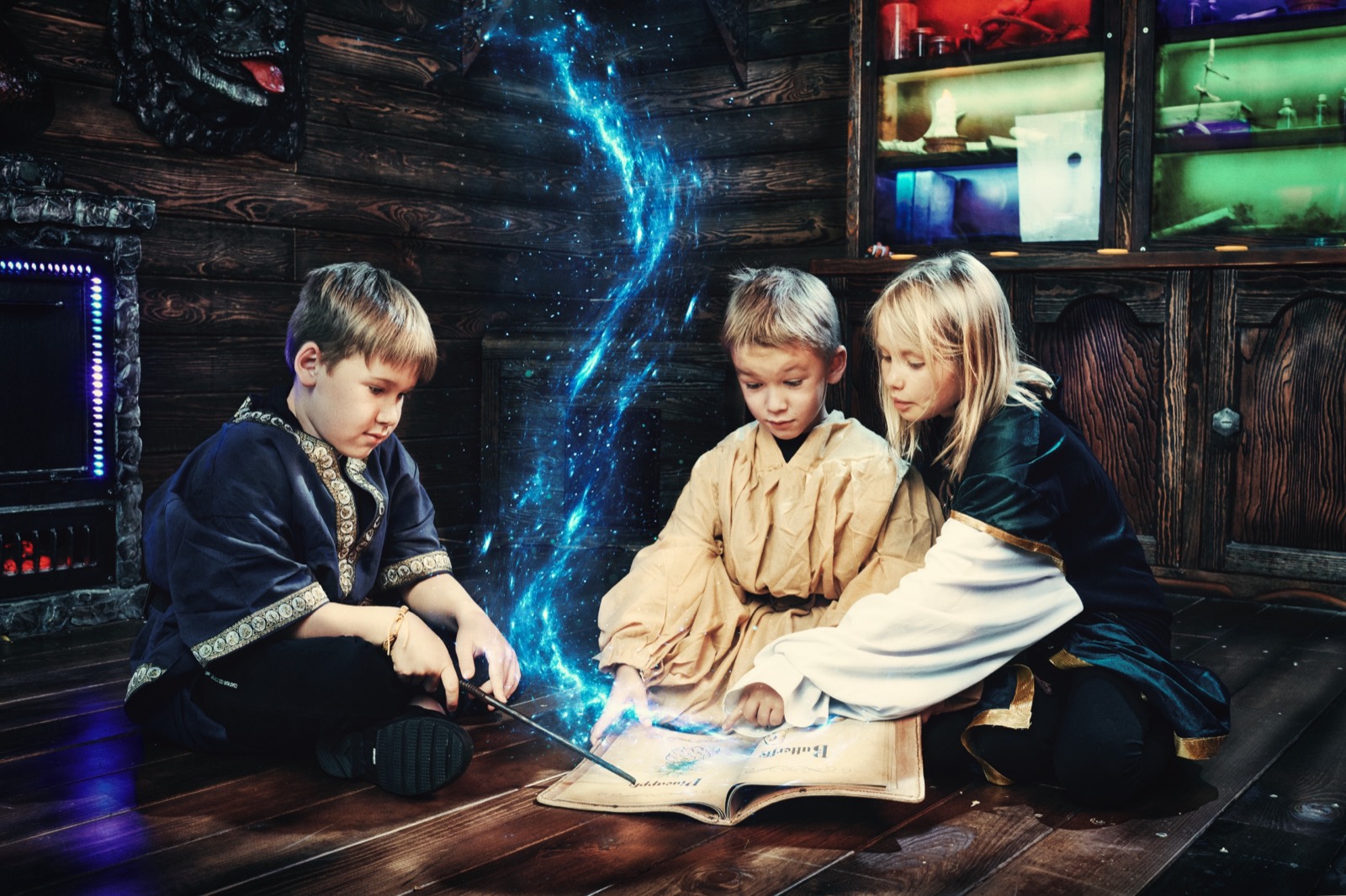 Kids at an escape room birthday party kneel over a spell book as blue magic rises inside Spell Breakers